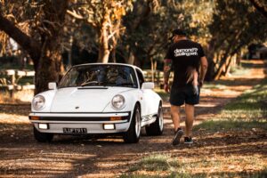 Diamond Detailing Perth walking toward a white classic Porsche 911 on a tree-lined path in Perth